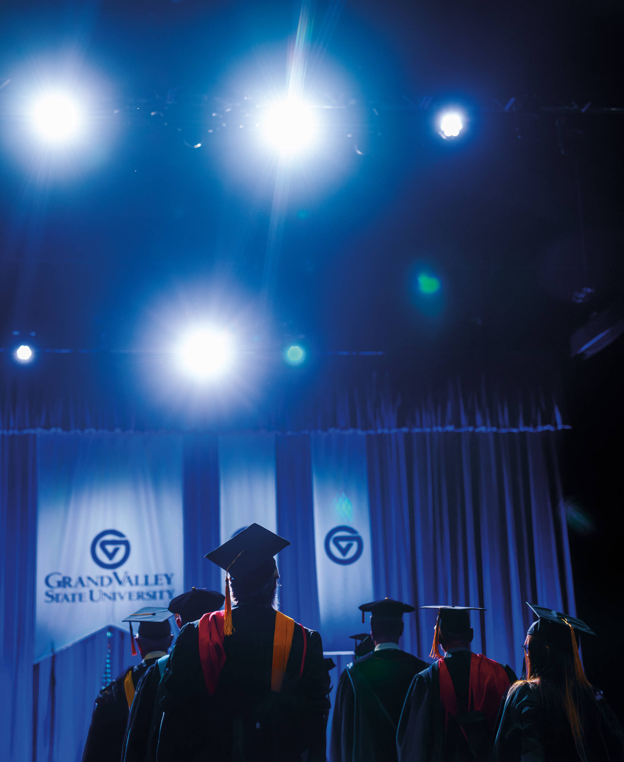 Graduates in caps and gowns face the stage during a commencement ceremony